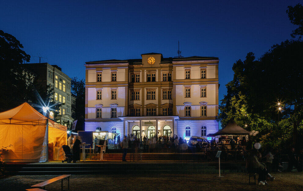 Hauptgebäude und Technikumplatz bei Nacht mit vielen Menschen