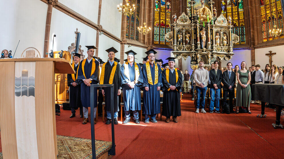 Blick in den Altarraum mit sitzenden Professor:innen und Erstsemestern.