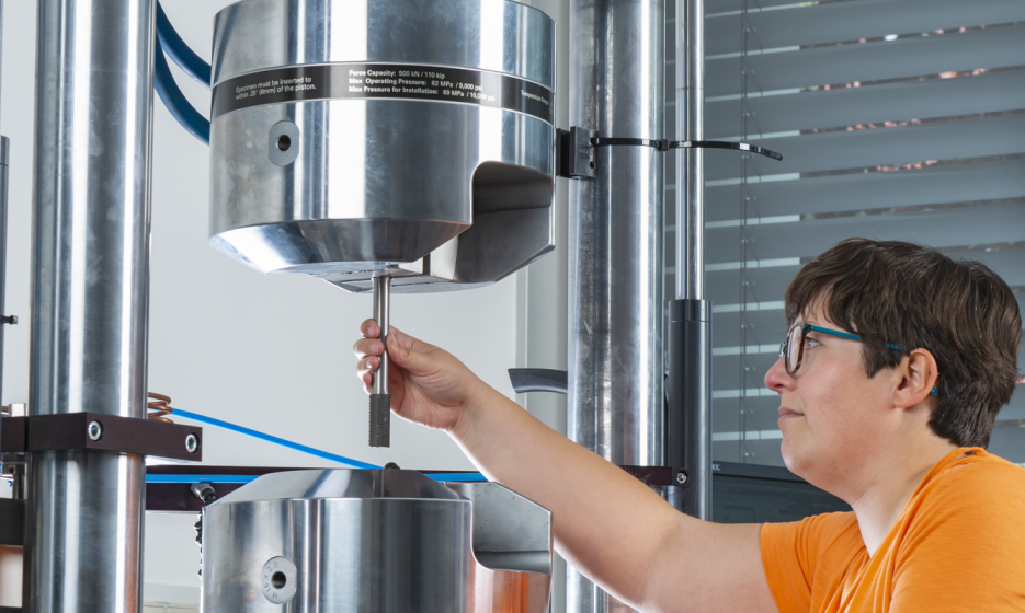 A woman is standing at a piece of equipment, securing a sample