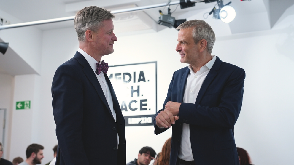 Two men are chatting, smiling.