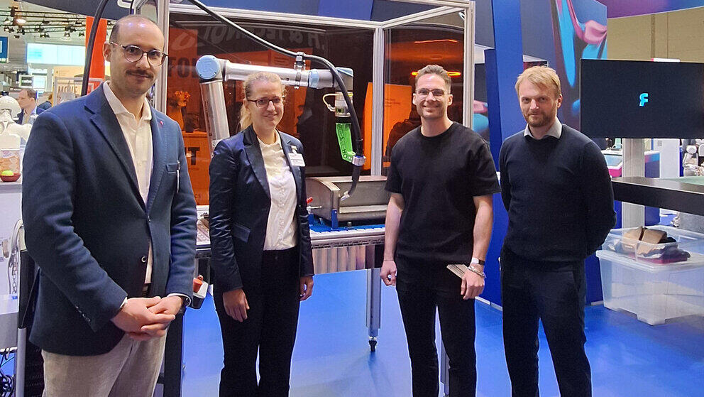 Vier Personen stehen an einem Messestand