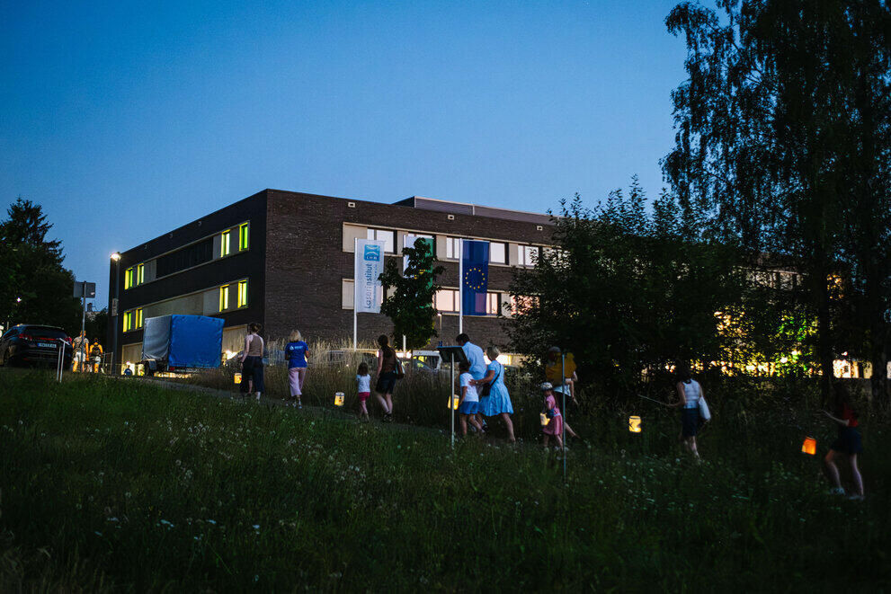 Outside the Laser Institute, a procession takes place in the dark, featuring children and other guests carrying homemade lanterns.
