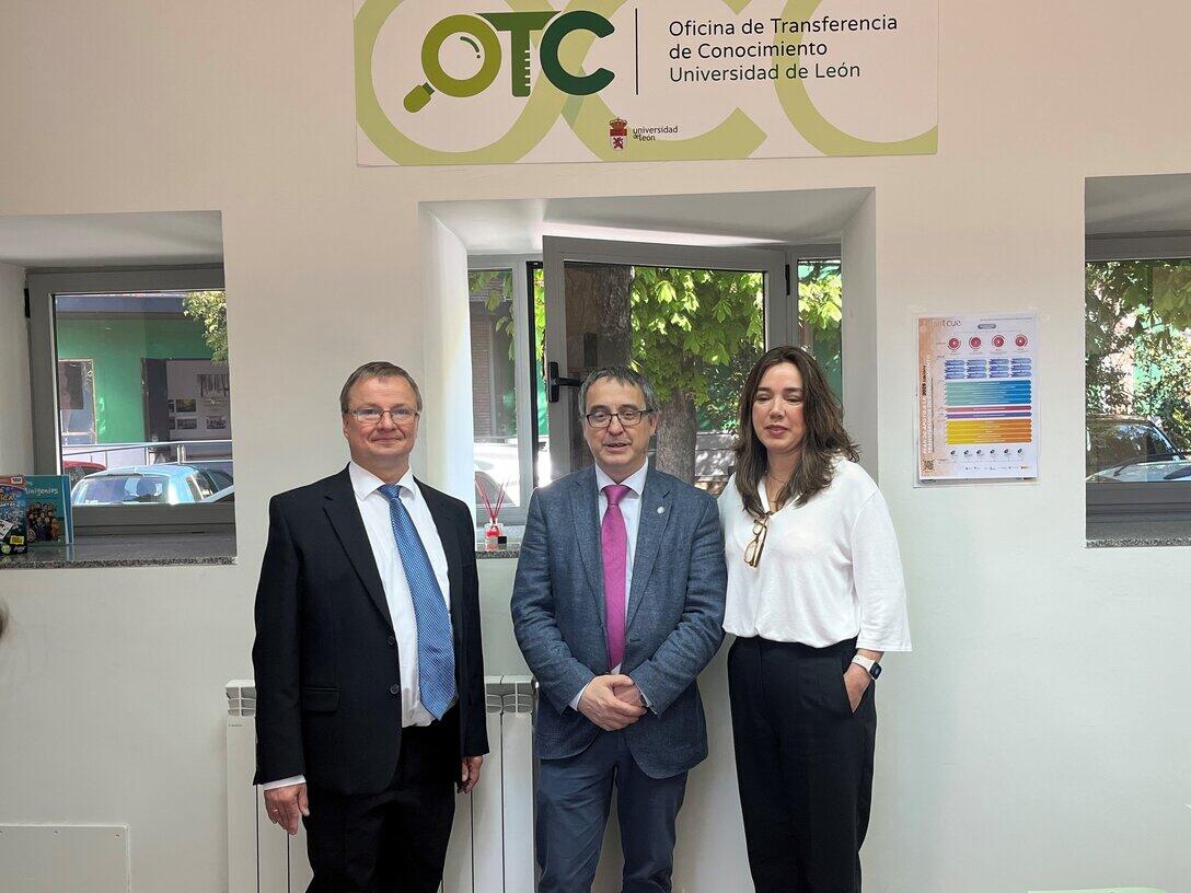 Zwei männliche und eine weibliche Person stehen vor einer Tür, über der das OTC-Logo angebracht ist