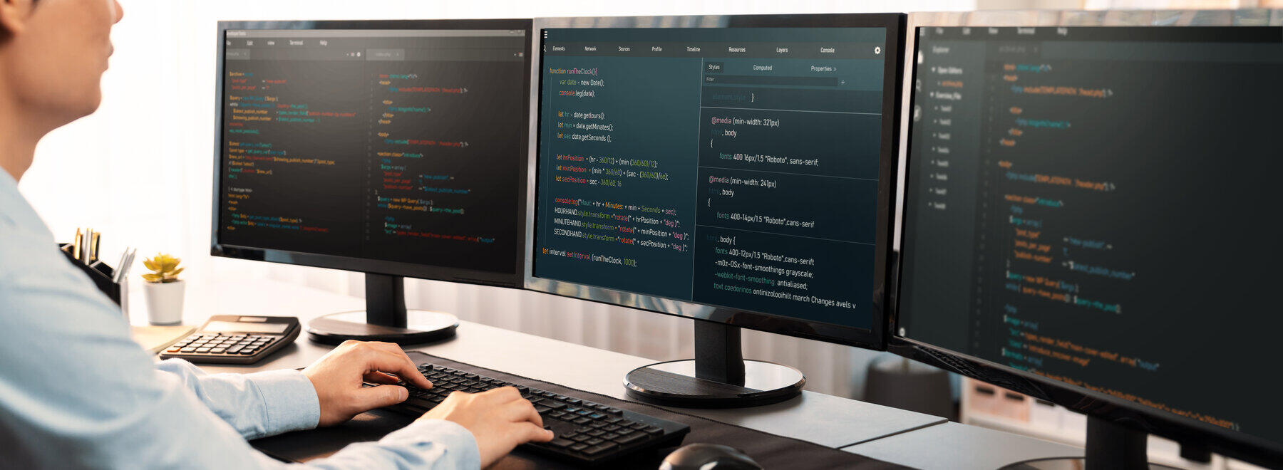 Ein Student sitzt vor Computerbildschirmen und programmiert.