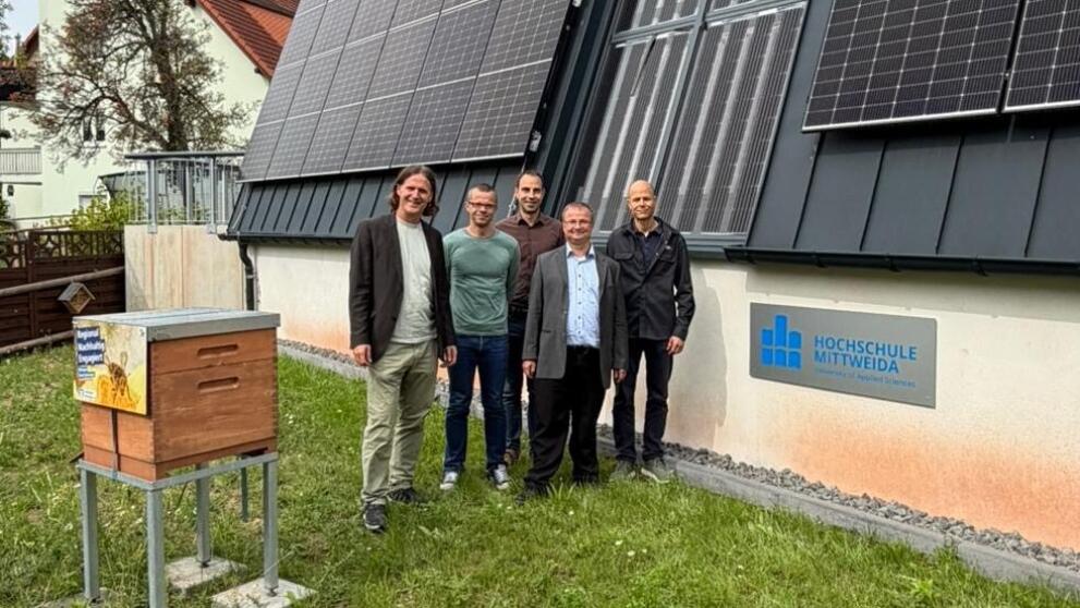 Fünf Personen stehen an einem Gebäude mit Solarpanels