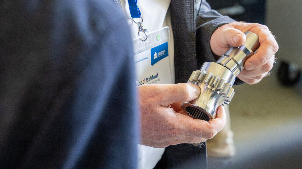 Detailaufnahme einer Hand, die ein Getriebeteil hält