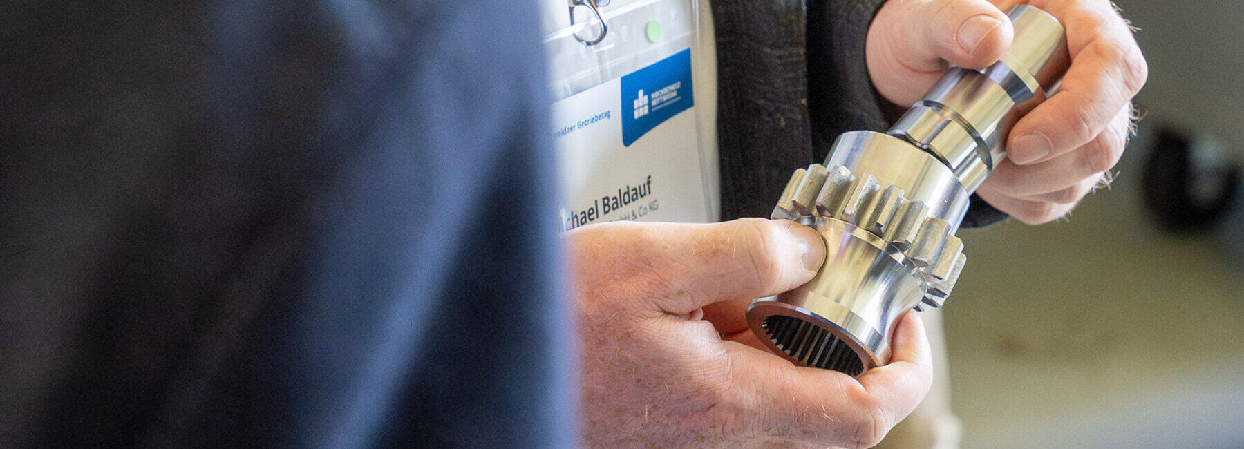 Detailaufnahme einer Hand, die ein Getriebeteil hält