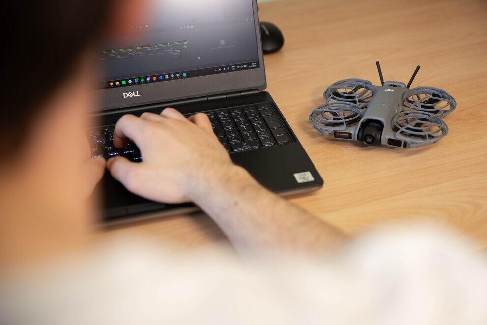 ein Student programmiert an seinem Laptop eine Drohne.