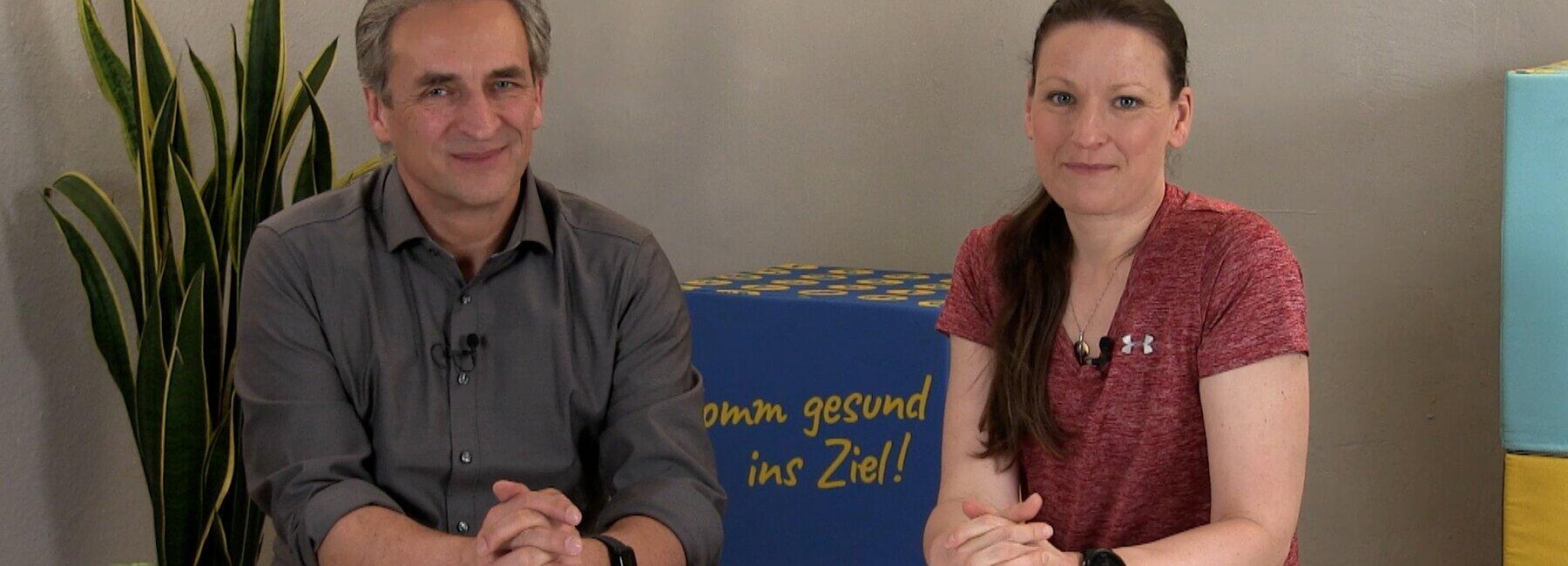 Eine männliche und eine weibliche Person sitzen nebeneinander an einem Tisch