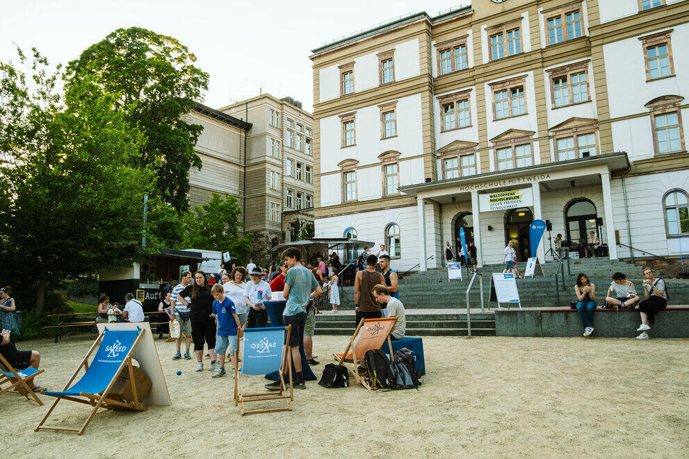 On Technikumplatz, guests are standing and sitting in the lounge, by the food truck or on the steps.