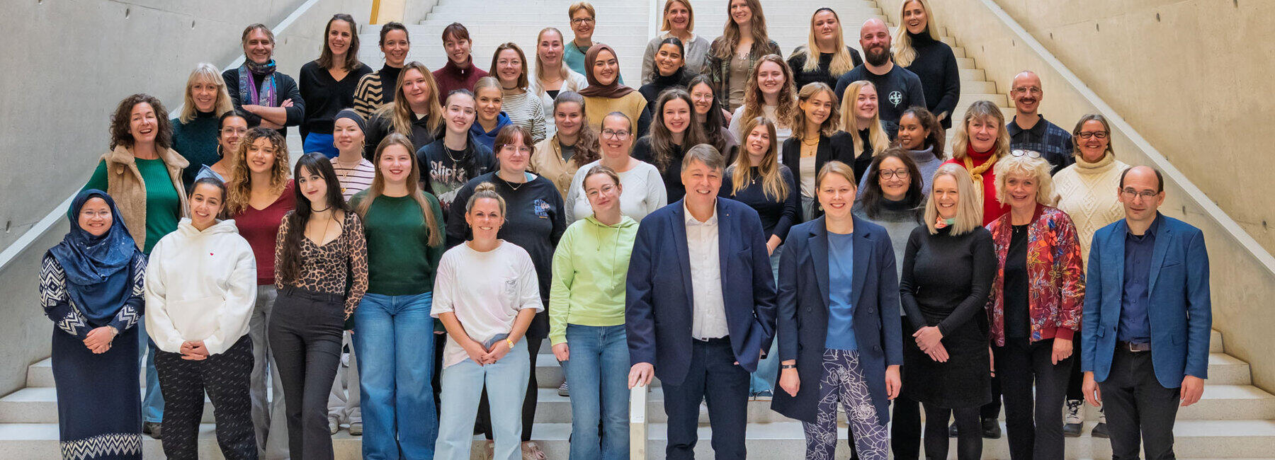 Gruppenfoto mit rund 50 Personen auf großer Treppe.