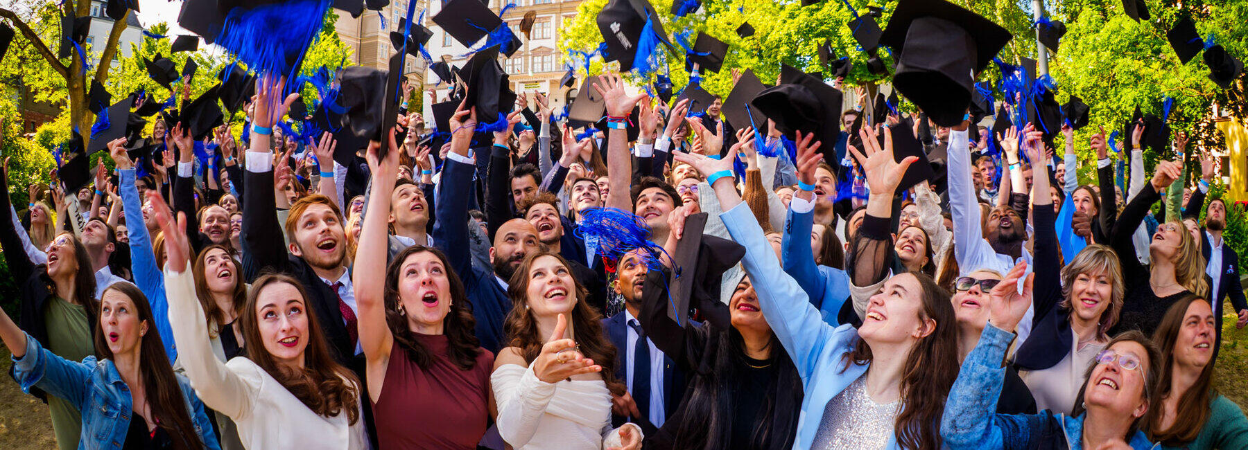 Lots of cheerful young people are throwing their graduation caps into the air.