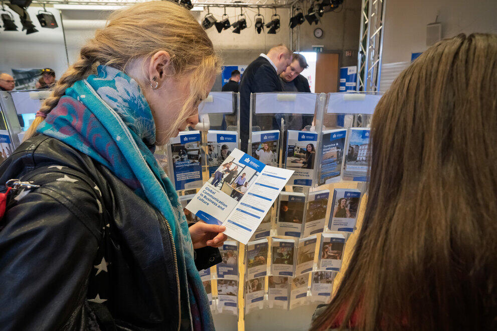 Zwei Studieninteressierte stehen vor zahlreichen Informationsflyern zu den einzelnen Studiengängen.