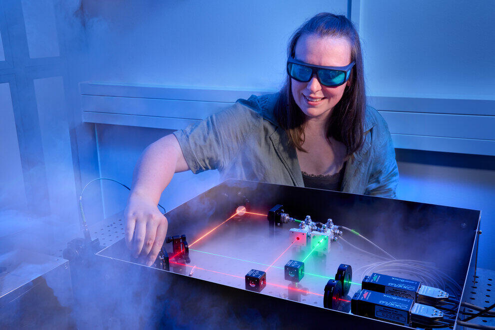 Eine Studentin mit Schutzbrille justiert einen Laserstrahlengang am Fluoreszenzmikroskop.
