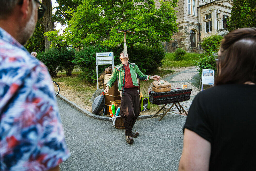 A juggler is balancing three knives on his chin.