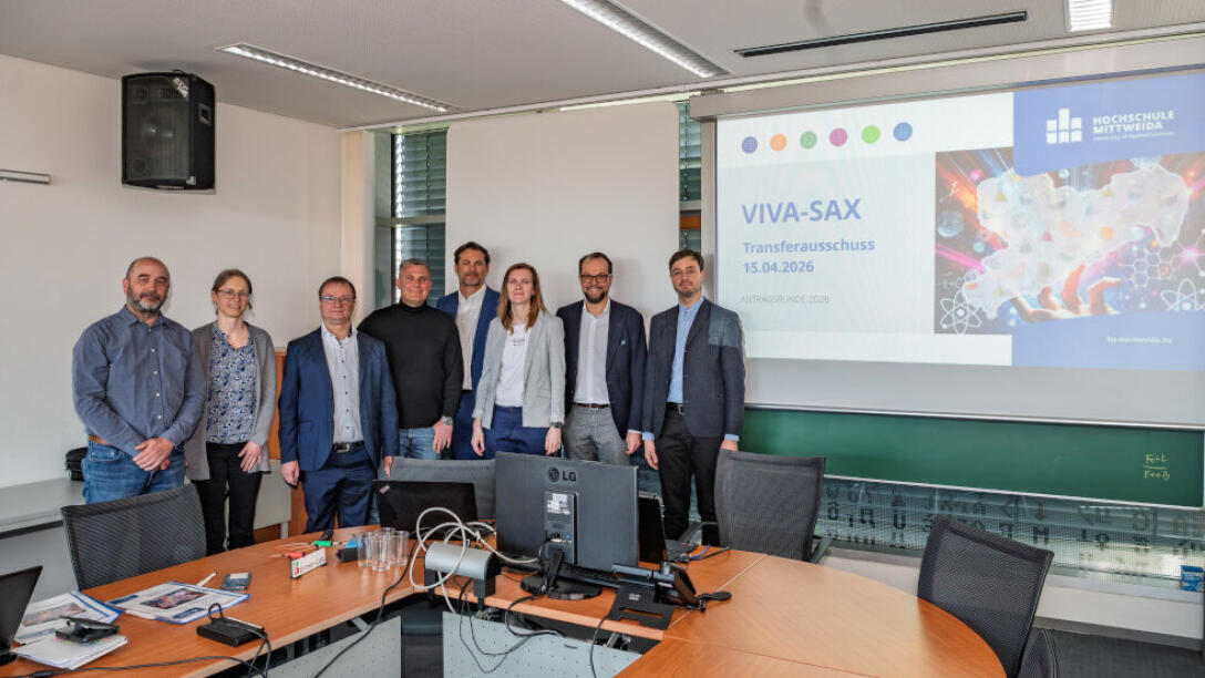 Gruppenbild: acht Personen stehen vor einer Präsentationswand