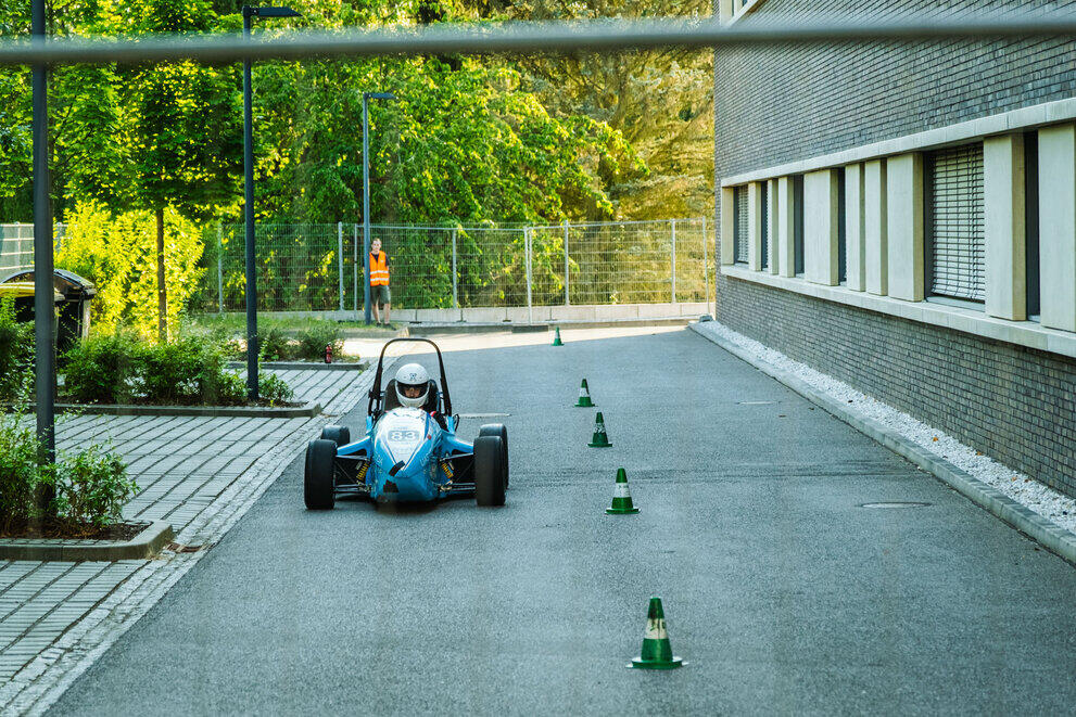 The race car belonging to Technikum Mittweida Motorsport is driving round a car park.