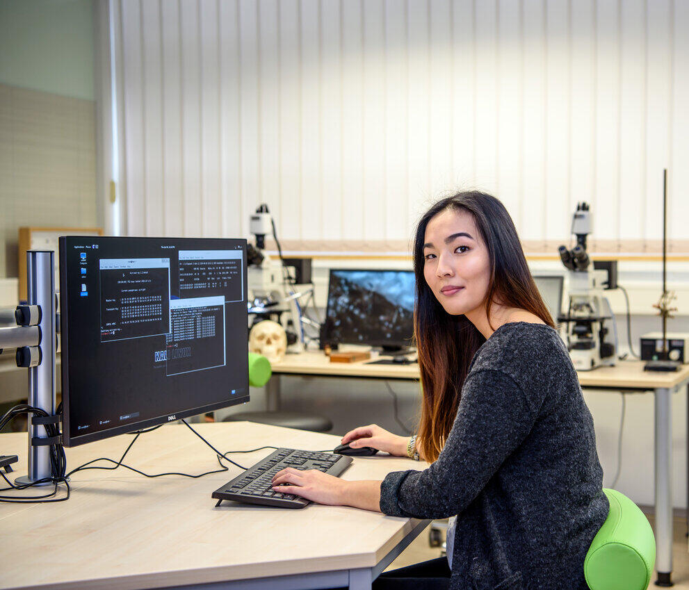 Eine Studentin sitzt vorm PC und analysiert Daten.