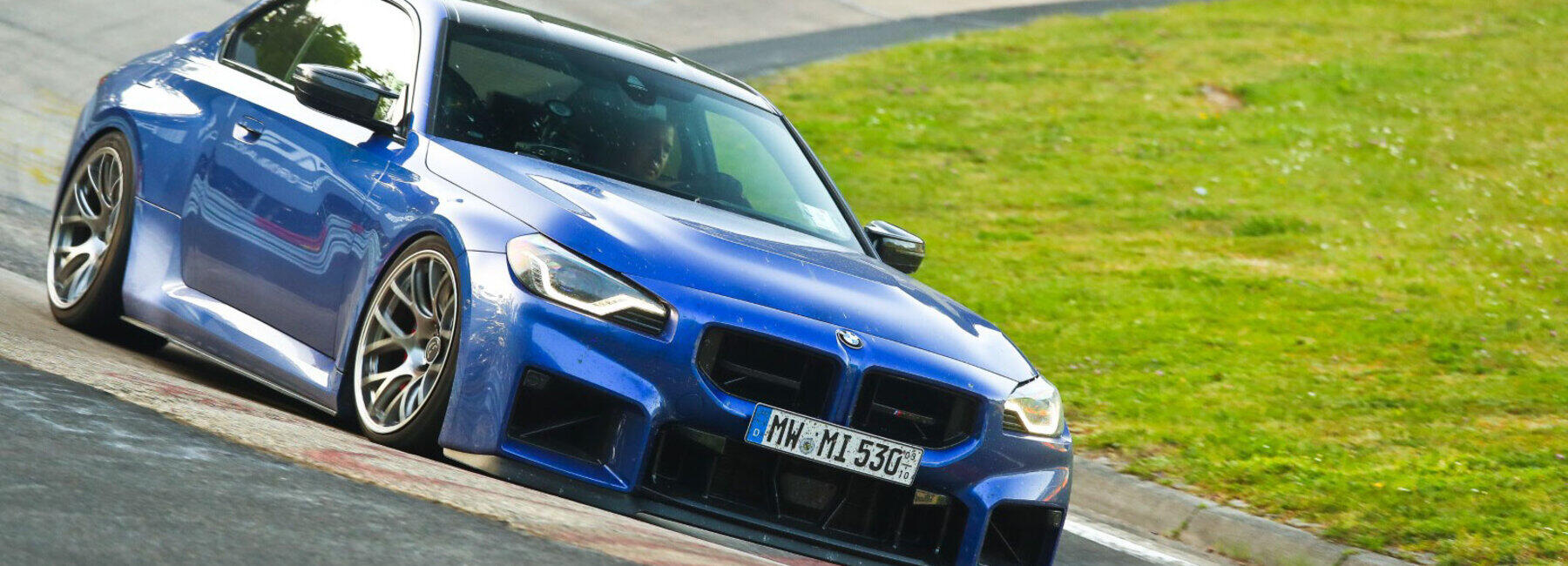 Ein blaues BMW Coupé in der Kurve einer Rennstrecke.