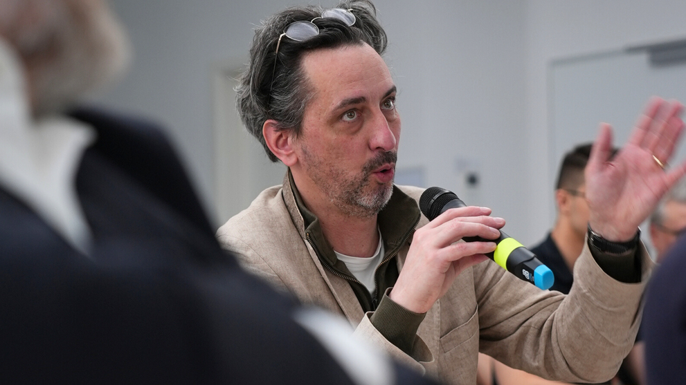 A man holding a microphone is speaking.