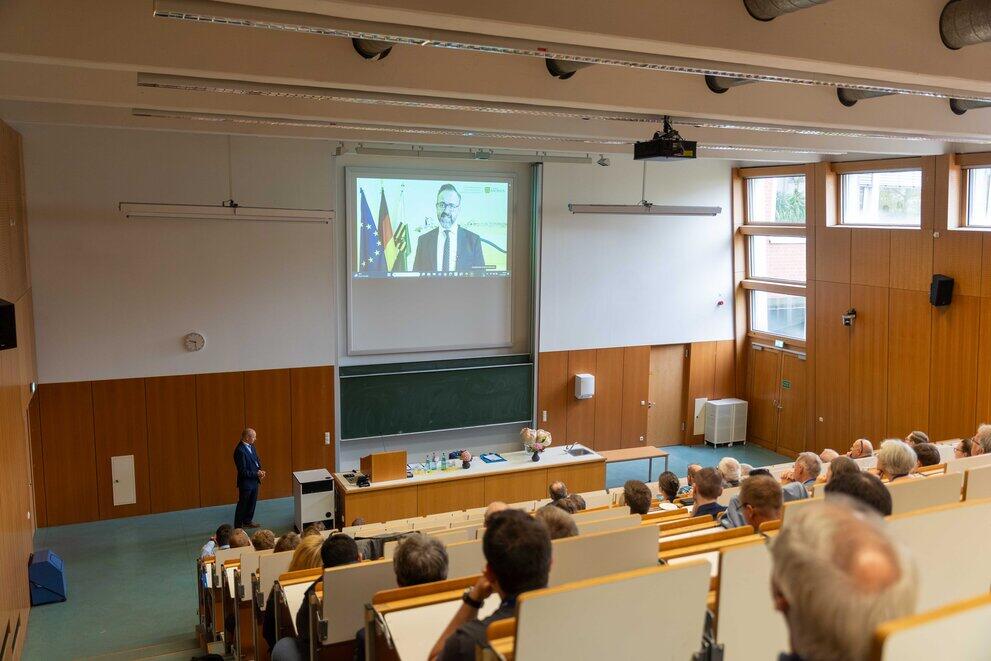 Blick in einen gefüllten Hörsaal mit einer Präsentationswand