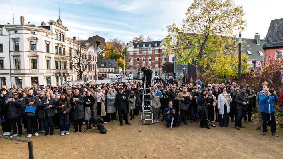 A reverse shot to the previous shot, showing the photographer on a ladder and the family members standing at the foot of the square.