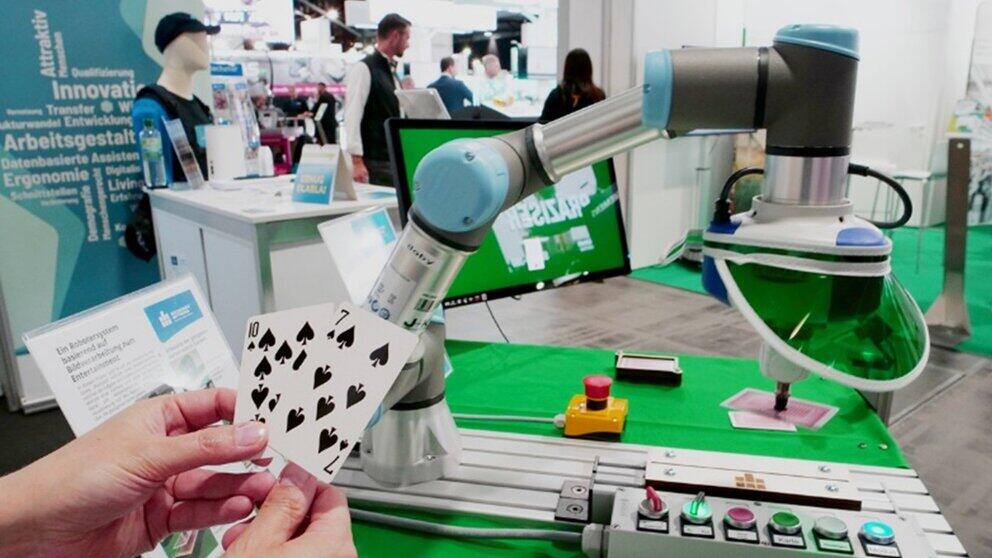 Blick auf Hände, die Karten halten und gegen einen Roboterarm spielen