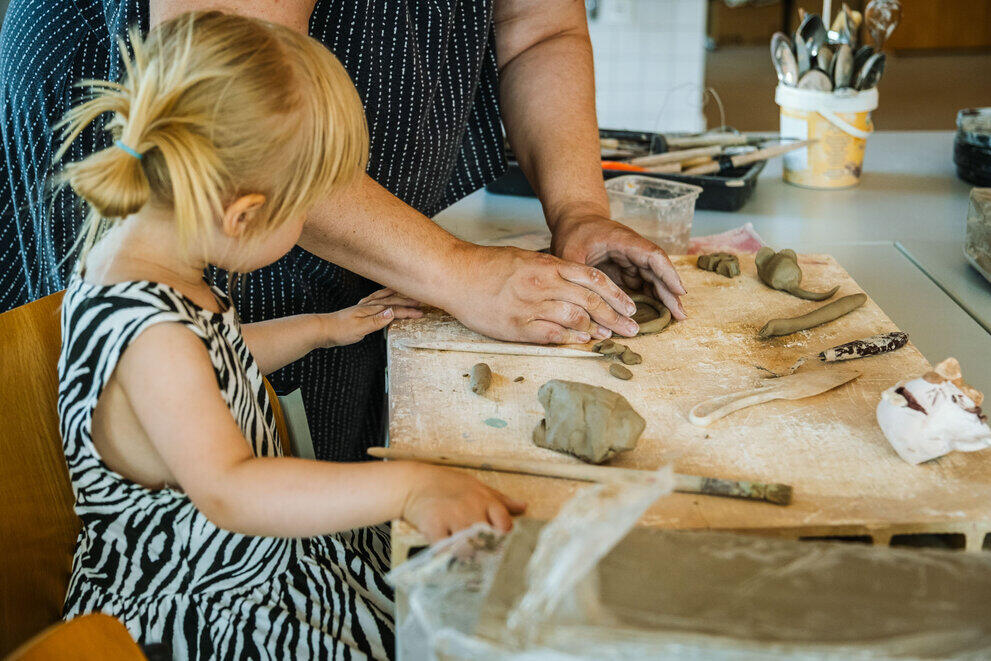 A child is shaping a form out of clay in the pottery workshop.