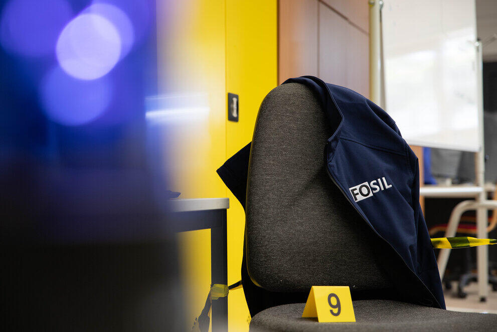 Eine Jacke mit der Aufschrift "FOSIL" hängt über einem Stuhl.