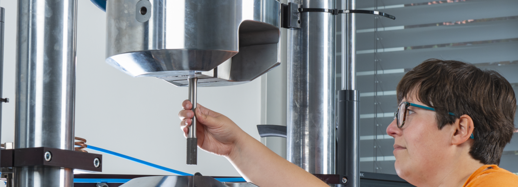 A woman is standing at a piece of equipment, securing a sample