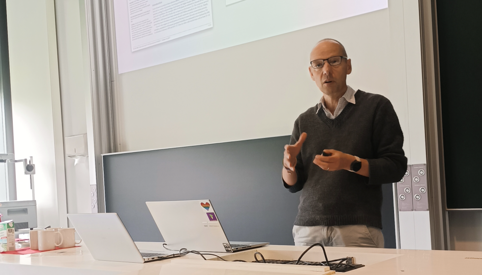A man giving a talk in front of a blackboard