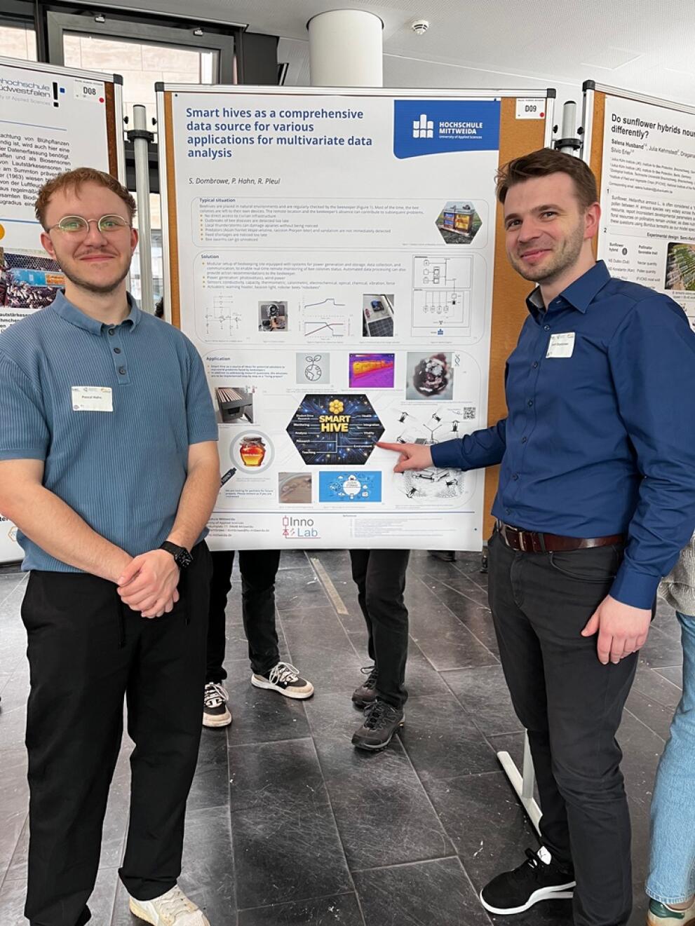 Two people are standing in front of a poster