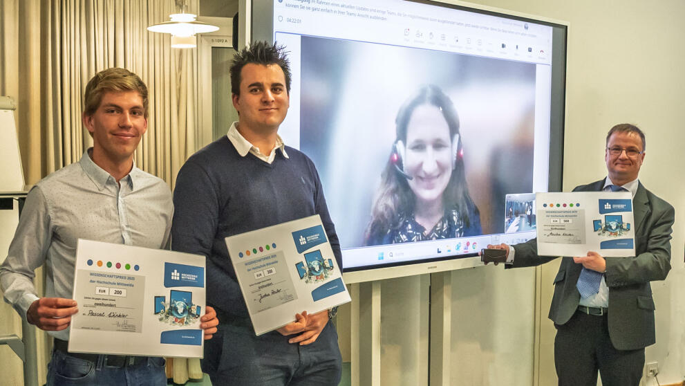 Three men holding documents. Between them, on a large screen, is a woman.