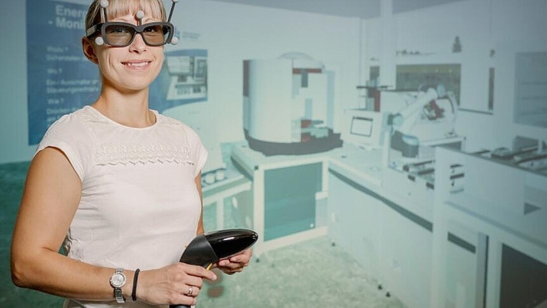 Weibliche Person mit VR-Brille steht vor Präsentationswand